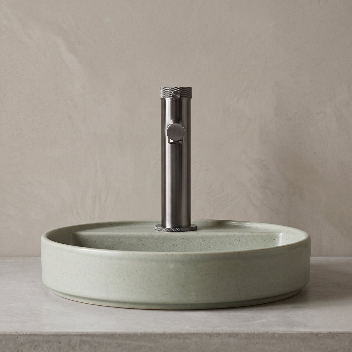 Robinet lavabo Aura gun metal au-dessus d'une vasque, vue rapprochée