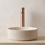 Robinet lavabo Aura or rose brossé au-dessus d'une vasque, vue rapprochée