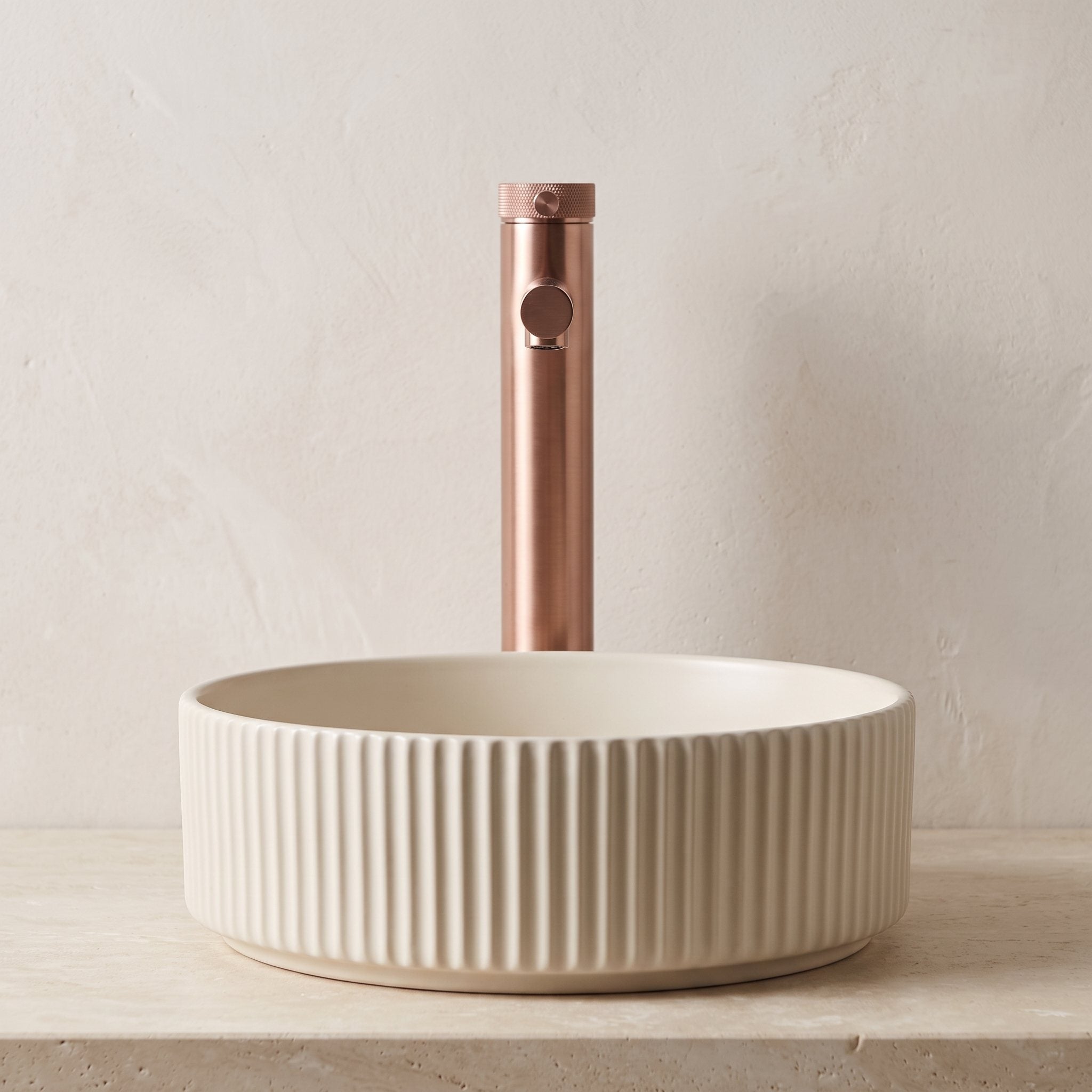 Robinet lavabo Aura or rose brossé au-dessus d'une vasque, vue rapprochée