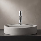 Robinet lavabo Dora Chrome Poli modèle standard vu de face derrière une vasque à poser