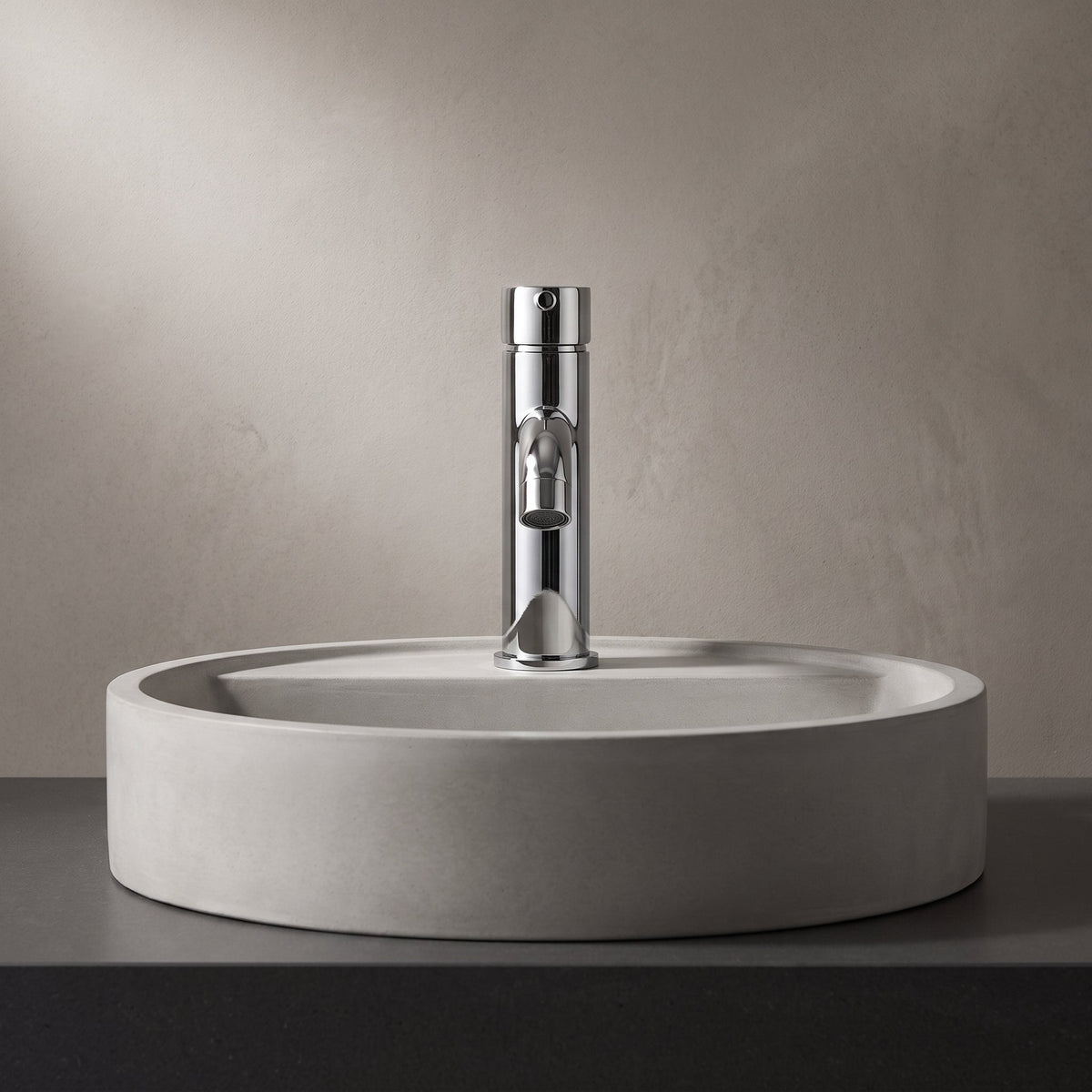 Robinet lavabo Dora Chrome Poli modèle standard vu de face derrière une vasque à poser