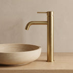 Robinet lavabo Dora Or Brossé modèle haut vu de profil sur une vasque en grès