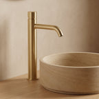 Robinet lavabo Dora Or Brossé modèle haut vu de profil à côté d'une vasque à poser