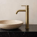 Robinet lavabo Dora Or Antique modèle haut vu de profil à côté d'une vasque à poser
