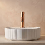 Robinet lavabo Dora Or Rose Brossé modèle standard vu de face derrière une vasque à poser
