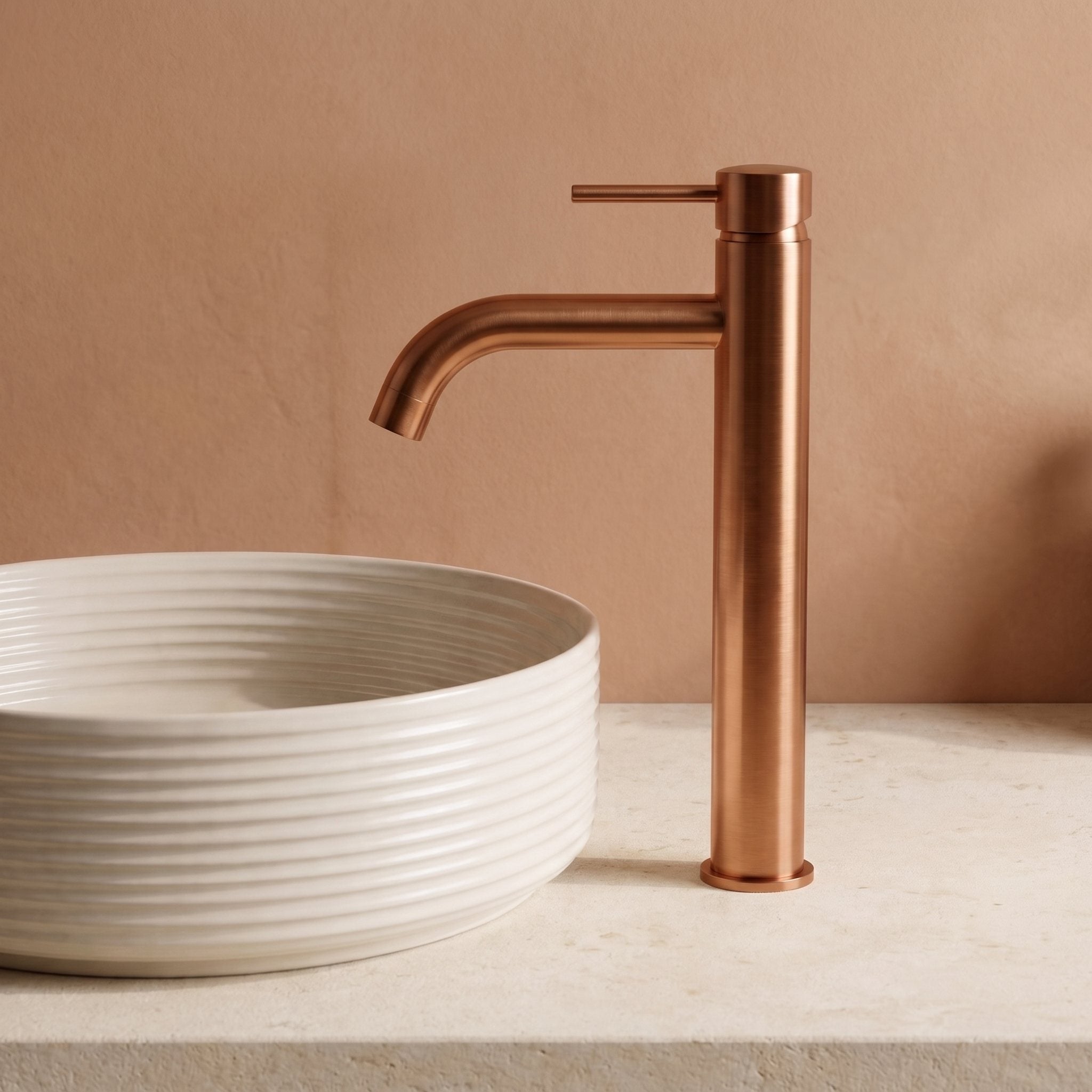 Robinet lavabo Dora Or Rose Brossé modèle haut vu de profil à côté d'une vasque à poser