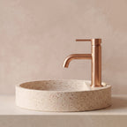 Robinet lavabo Dora Or Rose Poli modèle standard vu de profil près d'une vasque à poser