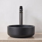Robinet lavabo Metra Gun Metal modèle haut vu de face derrière une vasque à poser