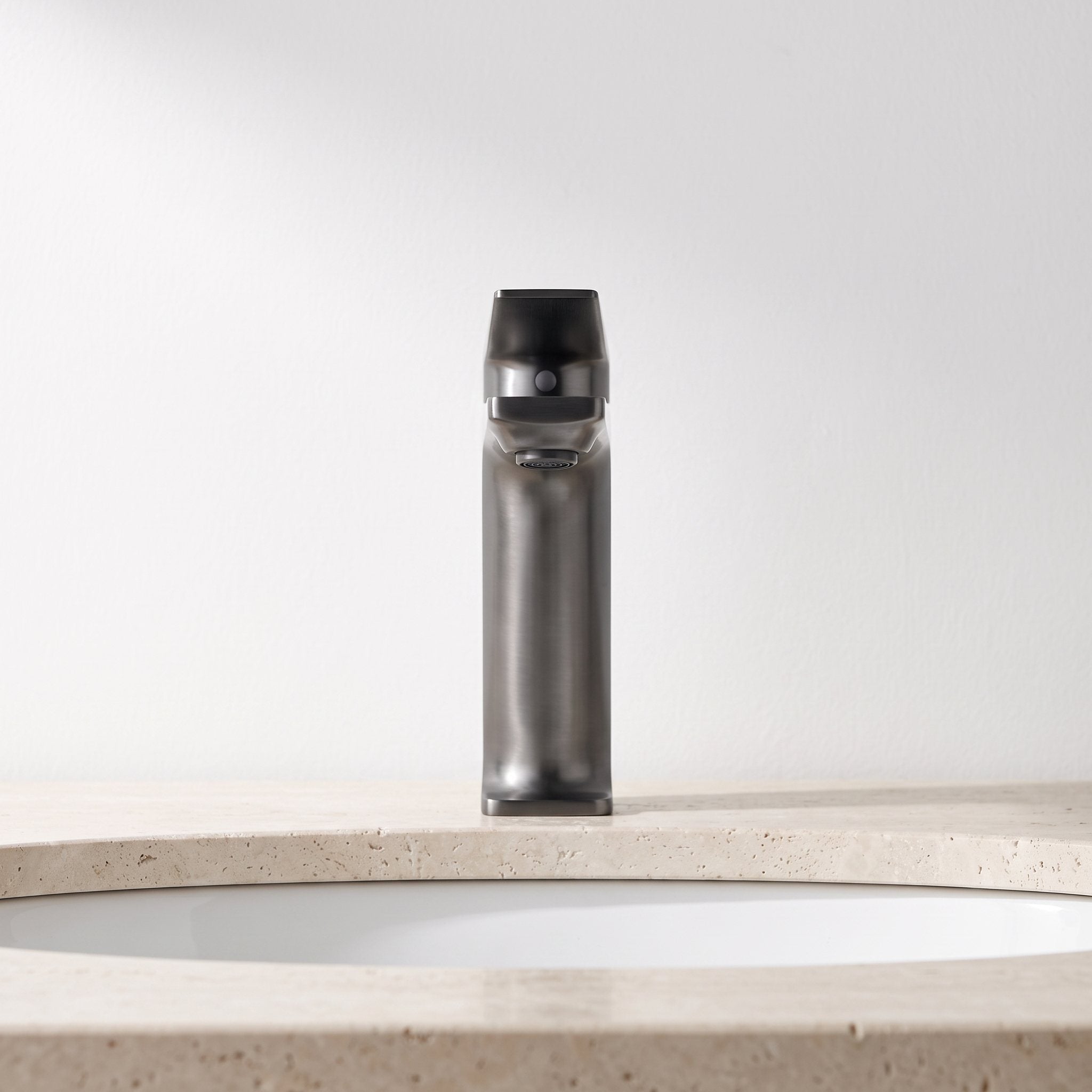 Robinet lavabo Metra Gun Metal modèle court vu de face sur un plan en travertin