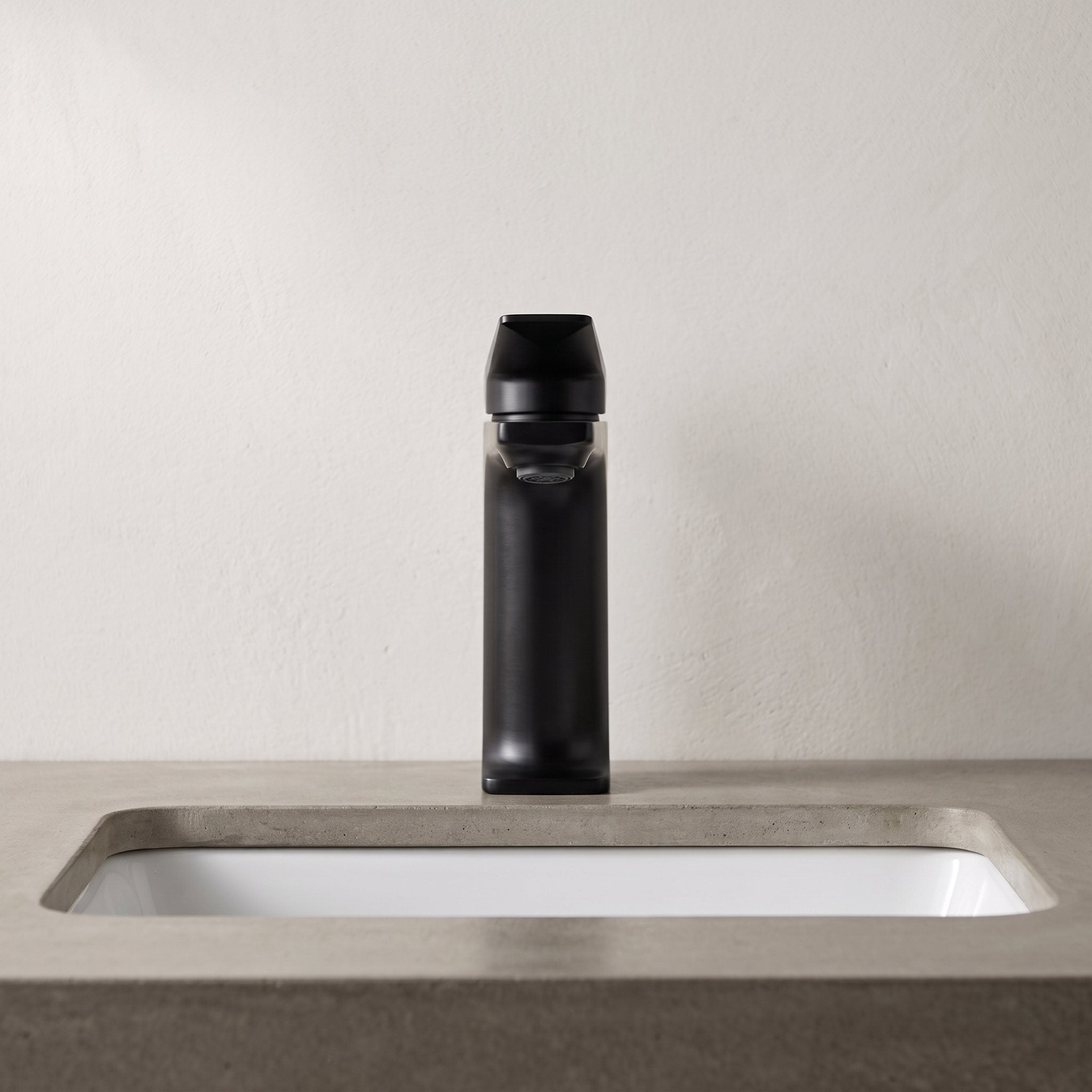 Robinet lavabo Metra Noir Mat modèle court vu de face sur un plan en béton