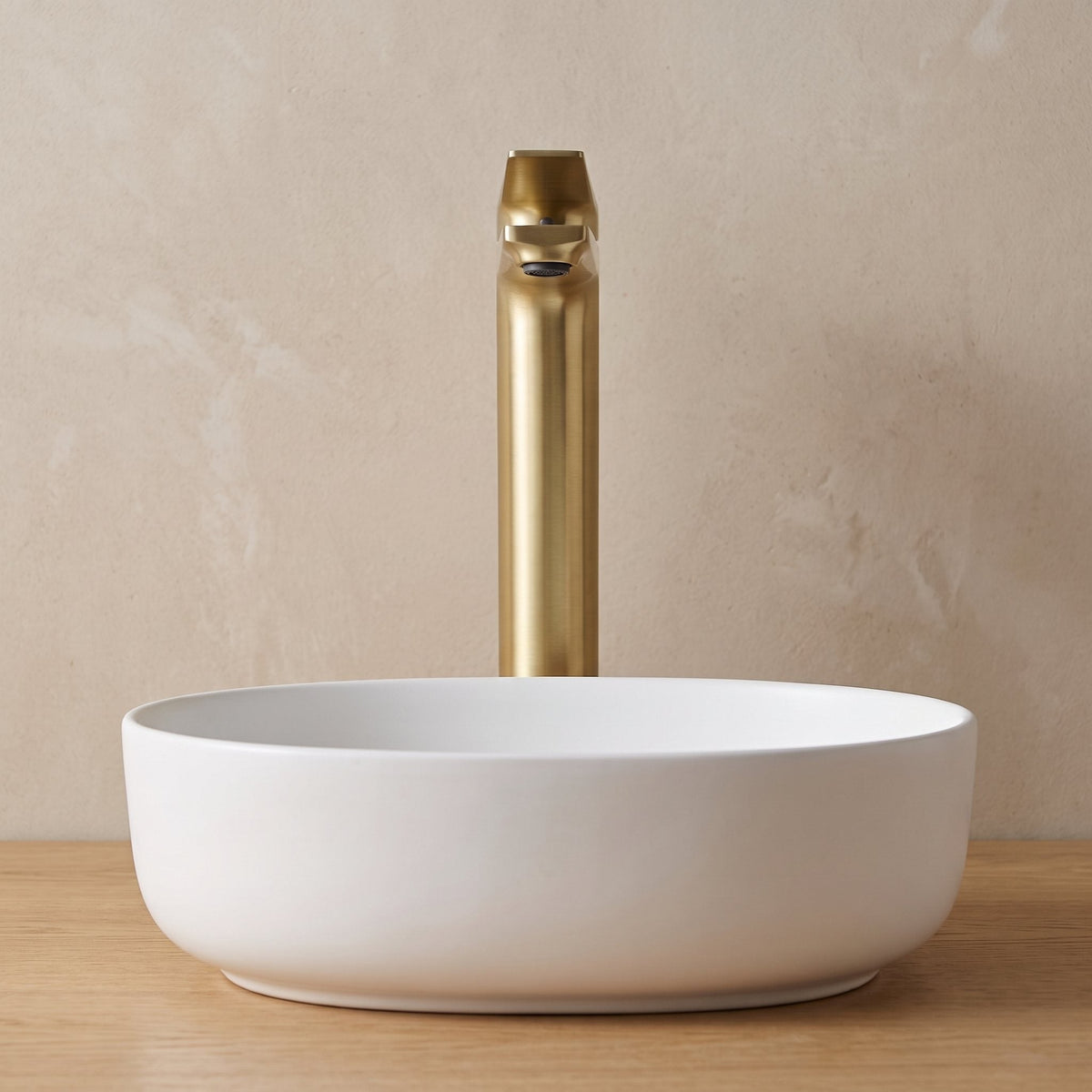 Robinet lavabo Metra Or Brossé modèle haut vu de face derrière une vasque à poser