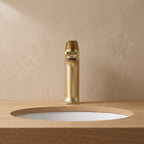 Robinet lavabo Metra Or Brossé modèle court vu de face sur un plan en chêne