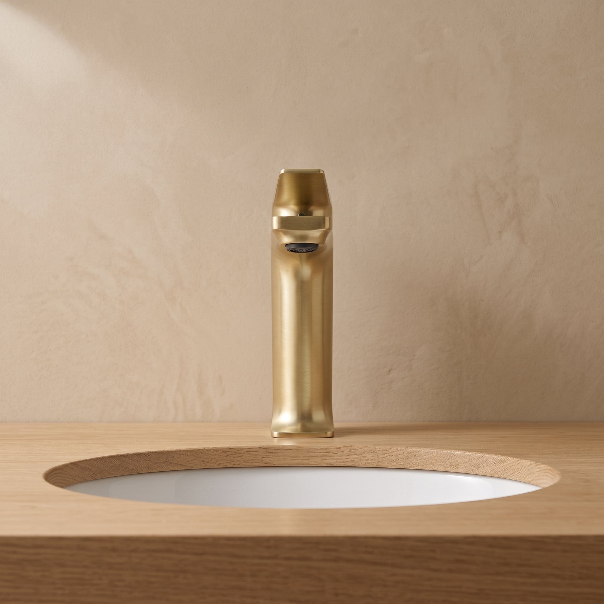 Robinet lavabo Metra Or Brossé modèle court vu de face sur un plan en chêne