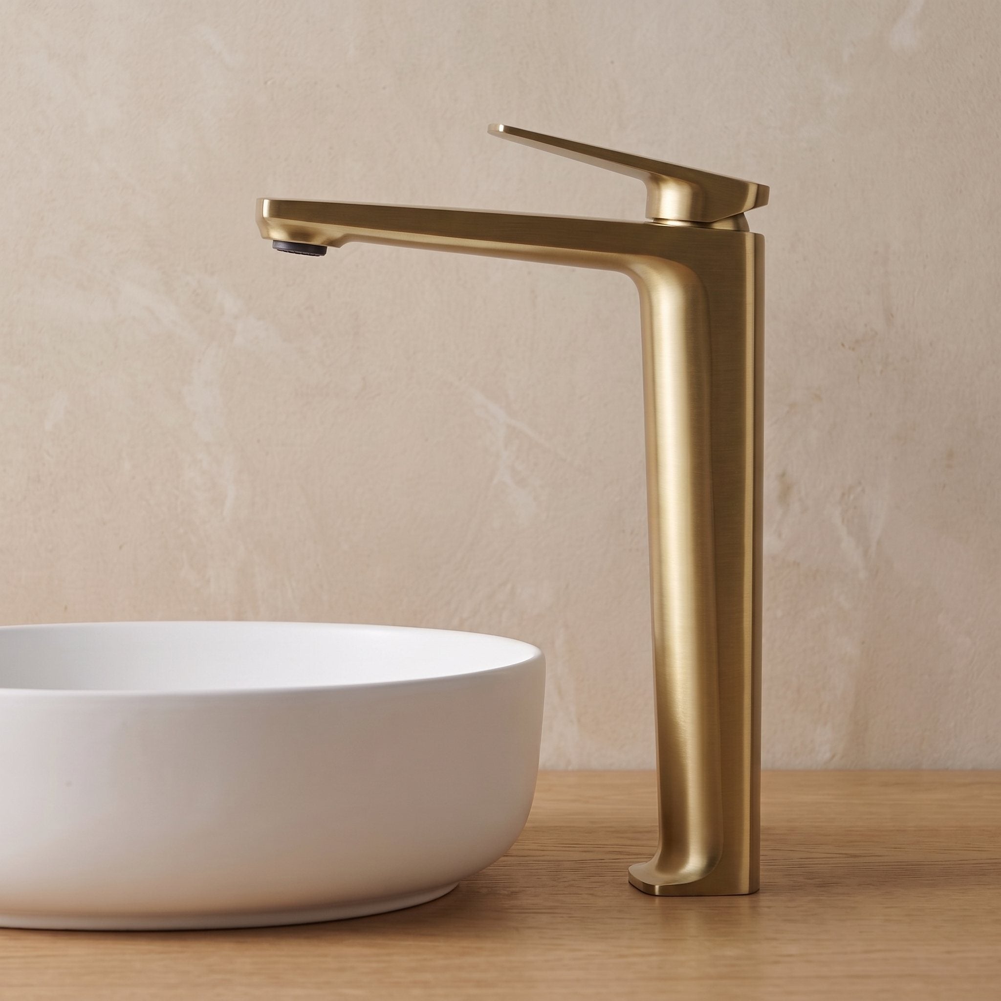 Robinet lavabo Metra Or Brossé modèle haut vu de profil derrière une vasque à poser