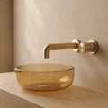 Robinet mural encastrable Muro or brossé au-dessus d'une vasque en verre ambré