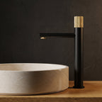 Robinet lavabo Runa noir mat et or brossé 318 mm derrière une vasque à poser, vue de profil