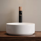 Robinet lavabo Runa noir mat et or rose 318 mm derrière une vasque à poser, vue de face