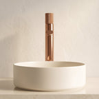 Robinet lavabo Runa or rose poli 318 mm derrière une vasque à poser, vue de face