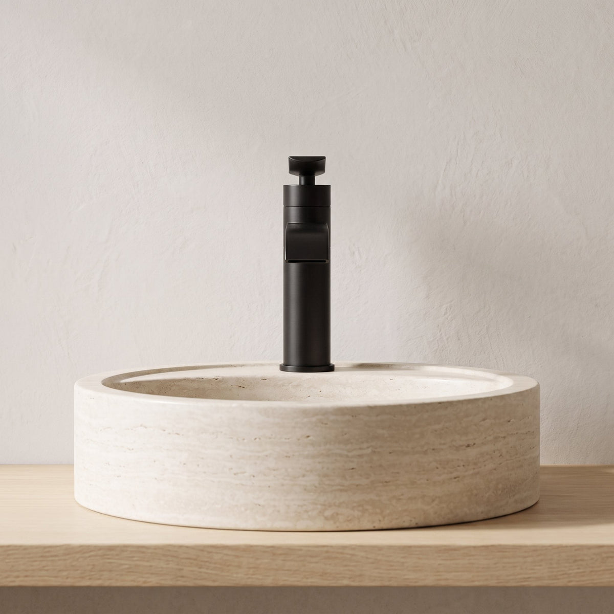 Robinet lavabo cascade Vetra noir mat sur une vasque en travertin